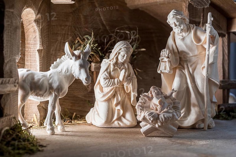 The Holy Family at the crib, wooden crib figurines represent the birth of Jesus Christ Child lying in a crib in a stable as a little Christ Child, Christmas