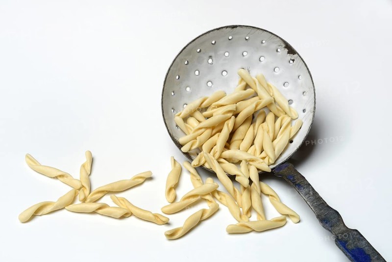 Strozzapreti, uncooked Italian pasta in a sieve, Italy