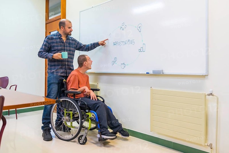 Man with disability and colleague talking during a creative brainstorming in a meeting room