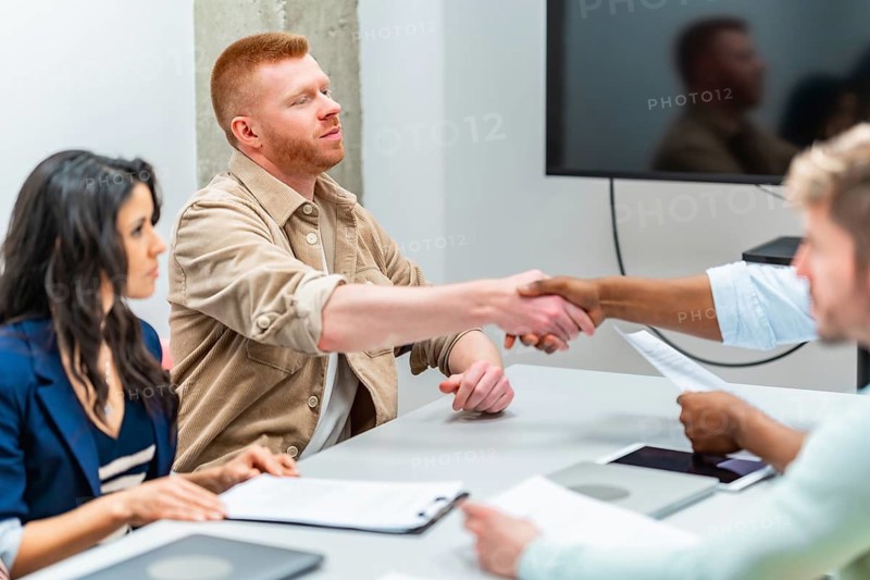 Business partners engaging in a handshake after finalizing a contract during an office meeting, highlighting teamwork and collaboration