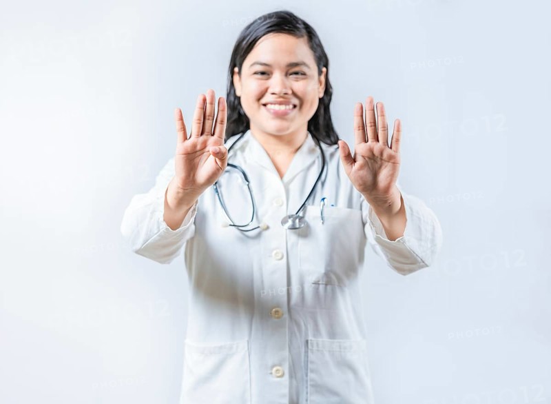 Asian female doctor counting number 9 on isolated background. Asian healthcare worker counting number nine isolated