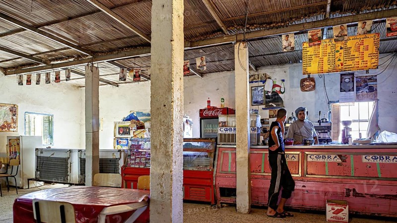 A rustic shop with a bar, posters on the walls and a relaxed atmosphere, a restaurant in a village in the Sahara in Algeria
