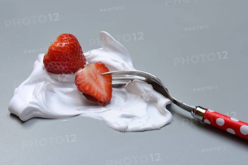 Strawberries on a fork with whipped cream