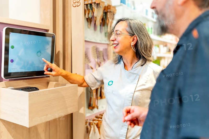 Man buying medicines on a technological and innovative store while female saleswoman using laptop to help him