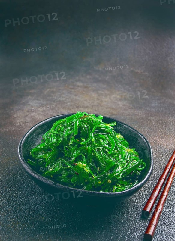 Chuka salad, made from fresh seaweed, with sesame dressing, served in a black bowl, with chopsticks