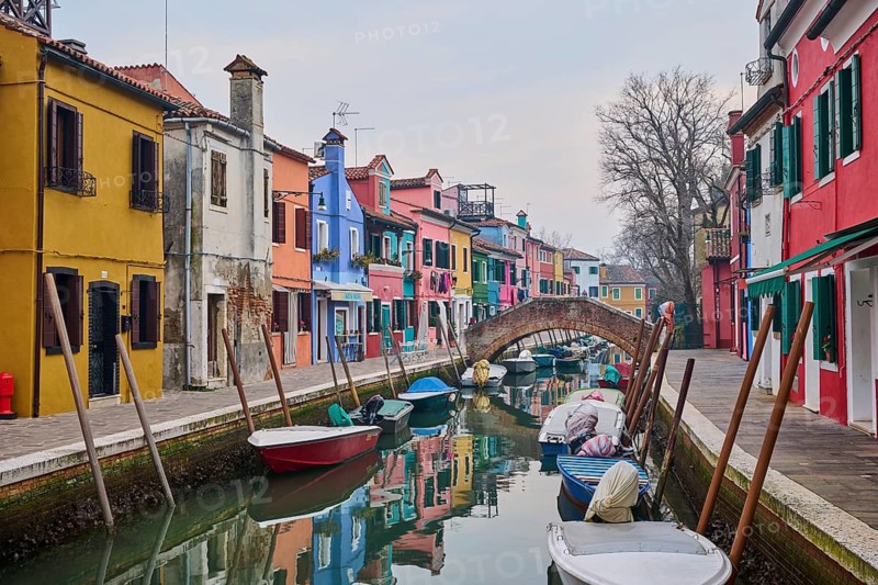Colorful houses beside the waterway in between 'Riva dei Santi' and 'Fondamenta di Terranova' with boats lying in the water on the island of Burano, Italy