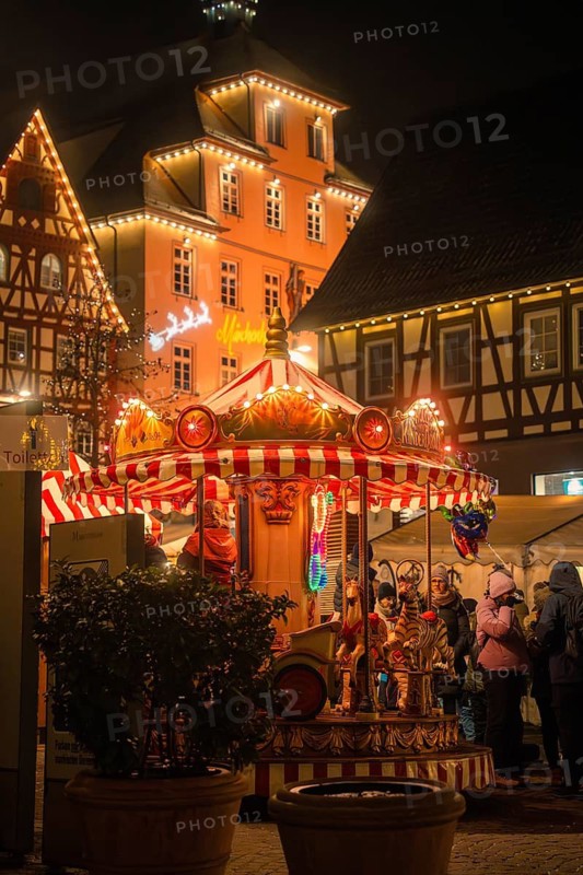 Festively illuminated carousel at a historic Christmas market at night, Christmas market Calw, Black Forest, Germany
