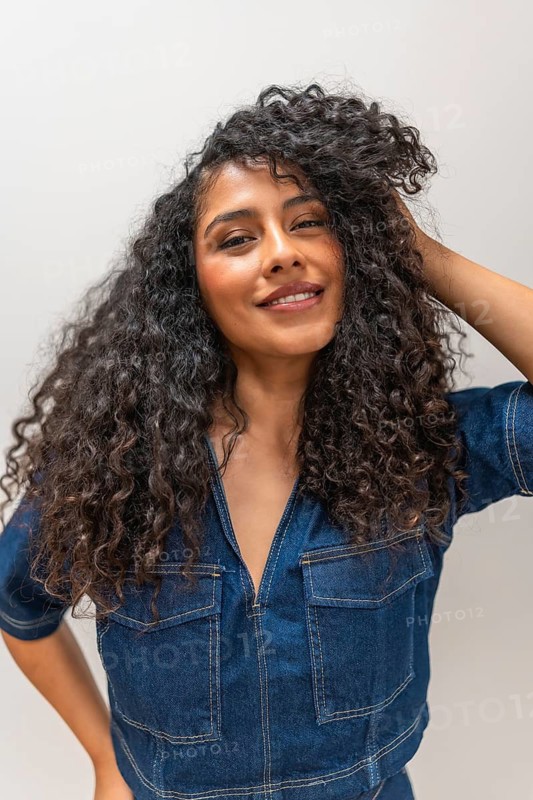 Vertical close-up portrait of a sensual latin woman hand on hair smiling at camera