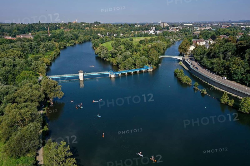 Mülheim an der Ruhr, North Rhine-Westphalia, Germany - Saarn-Mendener Ruhraue, green Ruhr area in Mülheim an der Ruhr. Stand-up paddlers in front of the Mülheim an der Ruhr weir. The Ruhr island in the centre. At the back right the city centre. At the back left the leather and tanning museum