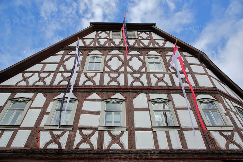 Historic half-timbered house Heimatspielhaus with flags, view from below, Münnerstadt, Rhön, Lower Franconia, Bavaria, Germany
