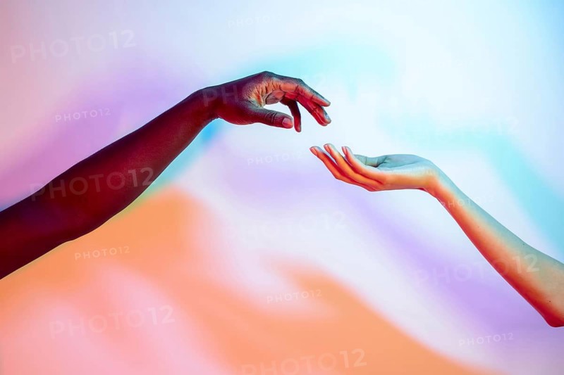 Two multiethnic hands reaching towards each other, set against a vibrant gradient backdrop, symbolizing connection and diversity, with bold, dynamic colors creating a harmonious atmosphere