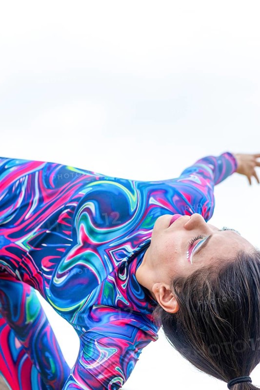 A woman in a colorful outfit passionately dances, embodying the spirit of LGBTQIA+ pride and creative expression. Her vibrant attire reflects fluidity and movement