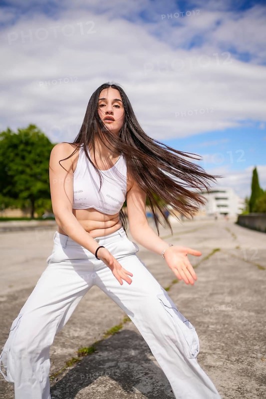Vertical photo of a caucasian young beauty woman dancing energetically freestyle in an urban park