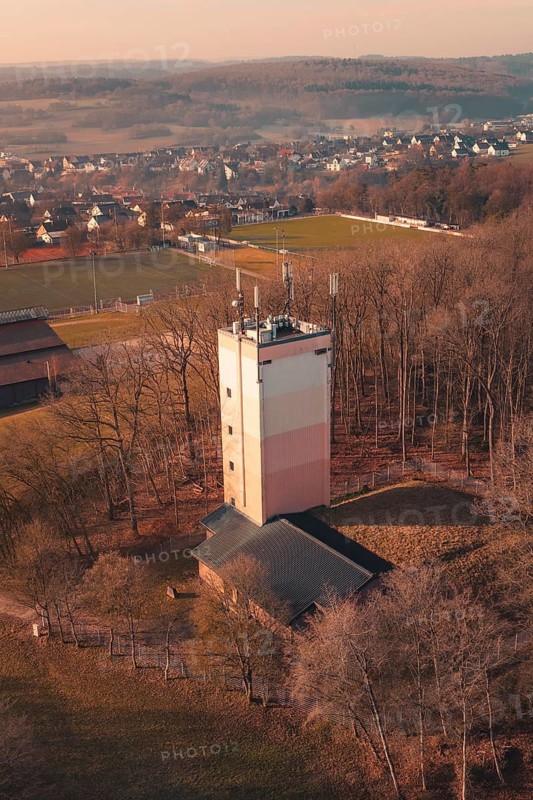 Water towerA tower rises from a wooded area near a village, landscape in cool pastel colors and winter atmosphere, Gechingen, Calw district, Germany