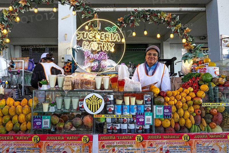 A friendly smiling woman from the indigenous population behind a stand with exotic fruits for the preparation of fresh fruit juice, weekly market market, market hall, Arequipa, southern Peru, Peru, South America