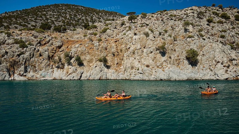 People enjoy paddling in kayaks along the rocky coast on the clear sea, Rina, harbour, Vathi, Vathys, Kalymnos, Dodecanese, Greek Islands, Greece