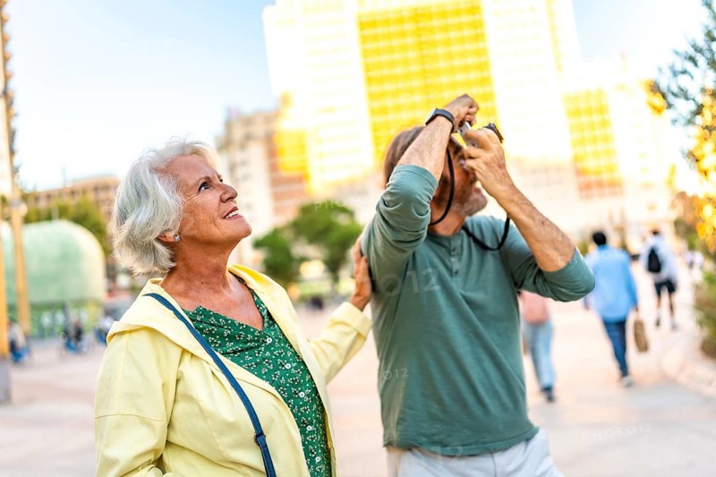 Senior man talking a photo with a digital camera while visiting the city with his partner