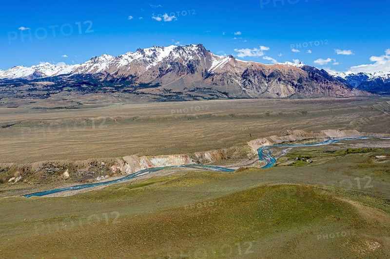 River flows in a canyon in front of snow-capped volcanic mountains, between Chile Chico and Jeinimeni National Park, aerial view, Patagonia, Chile