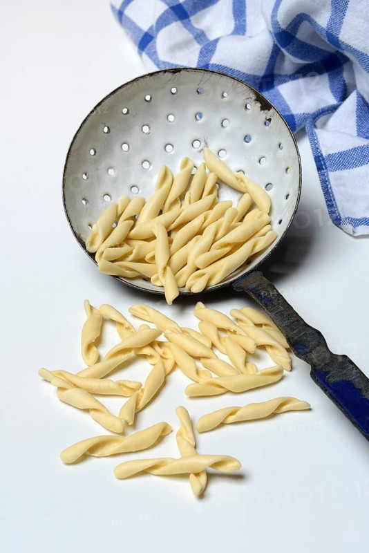 Strozzapreti, uncooked Italian pasta in a sieve, Italy
