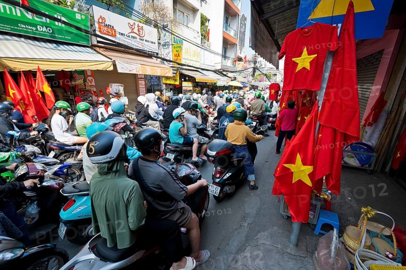 Countless people are on a motorcycle to the celebrations for the 50th anniversary of the reunification of Vietnam after the Vietnam War and stuck in traffic on a street decorated with Vietnamese national flags, Hochiminh City, Saigon, Vietnam
