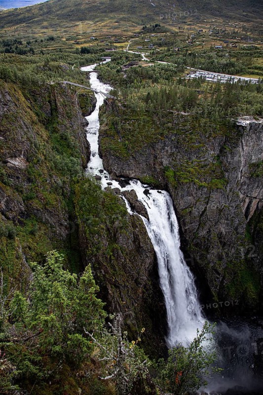 High waterfall that stretches through a narrow, tree-lined gorge, Voringsfossen, with a drop height of 165m, above the village of Eidfjord, Hardangerfjord, Norway, Scandinavia