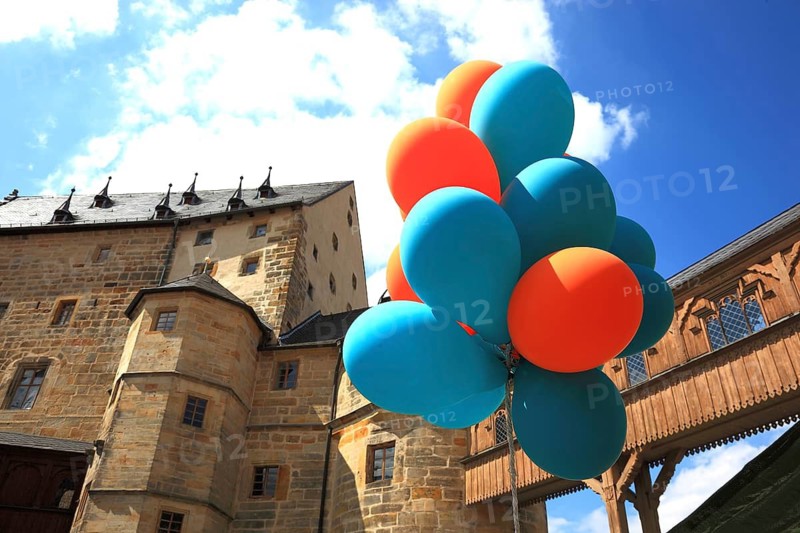 Colourful balloons in front of the transition to the castle seen from the Evangelical Lutheran St. Lawrence Church, Thurnau, Kulmbach district, Upper Franconia, Bavaria, Germany