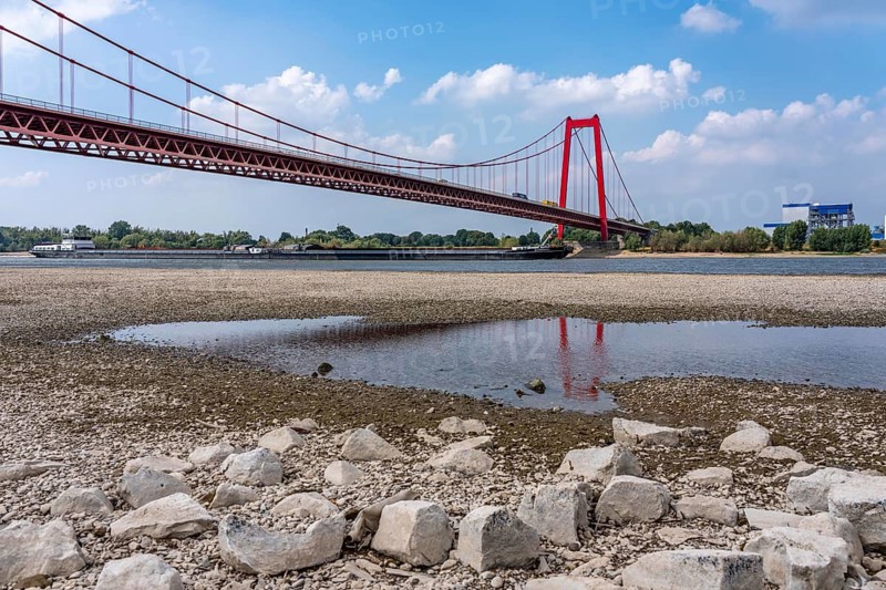 Rhine near Emmerich, extreme low water, Rhine level at 5 cm, downward trend, Emmerich Rhine bridge, cargo ships must travel with sometimes only 30 percent of the usual load, backdrop of the KLK Emmerich chemical plant, for oleochemical products, North Rhine-Westphalia, Germany