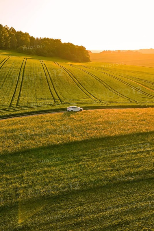 A car drives alone through the fields under a golden evening sky at sunset, Tesla Model Y, Gechingen, Calw district, Germany