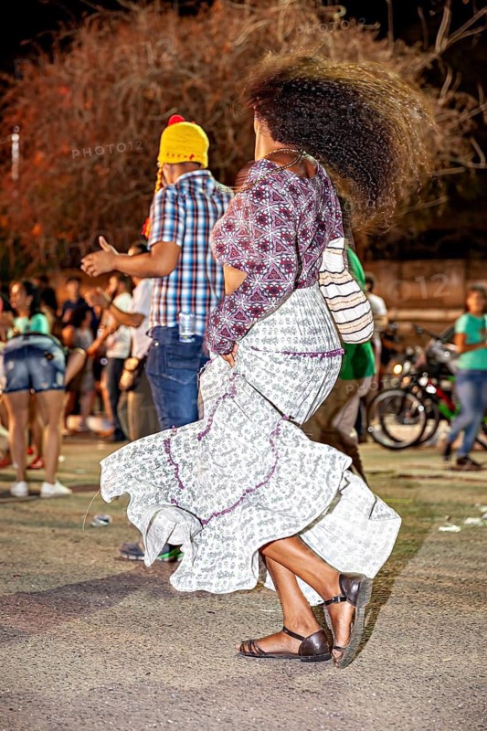 Woman with waving hair dances happily at night among people outdoors, joy and dancing at a festival in Petrolina in Brazil