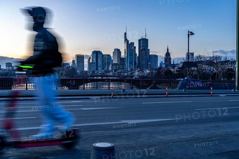 Skyline of the city centre of Frankfurt am Main, e-scooter on the raft bridge, dusk, river Main, winter, Hesse, Germany