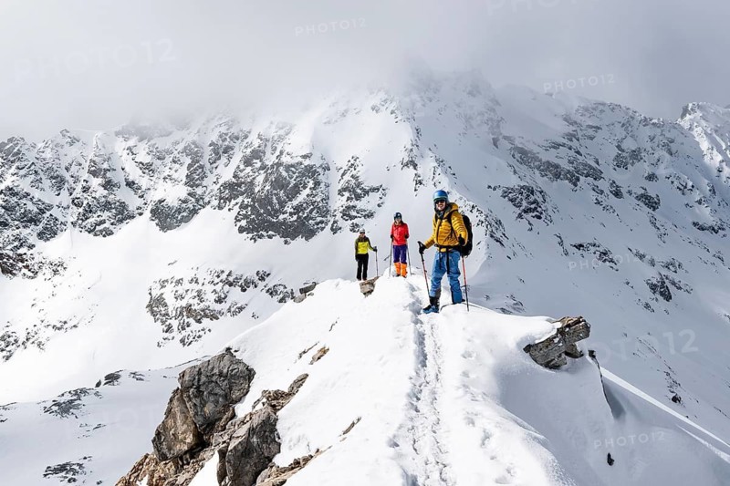 Three mountaineers climbing up the narrow mountain ridge of Piz Laviner, view of wintry mountain landscape, Grisons Haute Route, Albula Alps, Rhaetian Alps, Grisons, Eastern Switzerland, Switzerland