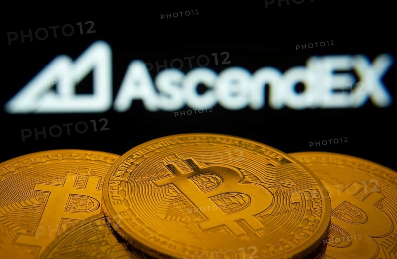 Dhaka, Bangladesh- 02 June 2025: Close-up of Bitcoin coins with the AscendEX logo visible on a screen in the background