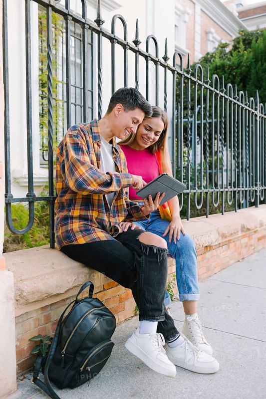 A happy lesbian couple enjoys a joyful moment together, sharing a laugh while looking at a tablet. Their happiness reflects love, inclusivity, and LGBTQIA+ pride
