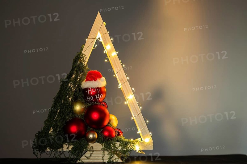 Modern DIY wooden Christmas tree with LED lights, moss, red balls and ornaments on a neutral background