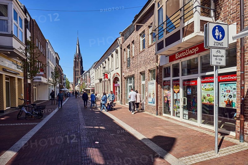 Pedestrian zone, general architecture, residential buildings and commercial buildings, pedestrian zone road sign with additional sign cyclists free 19-10 h, church tower of the Basilica of St. Marien, shops, shopping, Schum EuroShop, discount store, pedestrian as a side motif, city stroll, blue sky, cloudless, main street, Kevelaer, Kleve district, North Rhine-Westphalia, Germany
