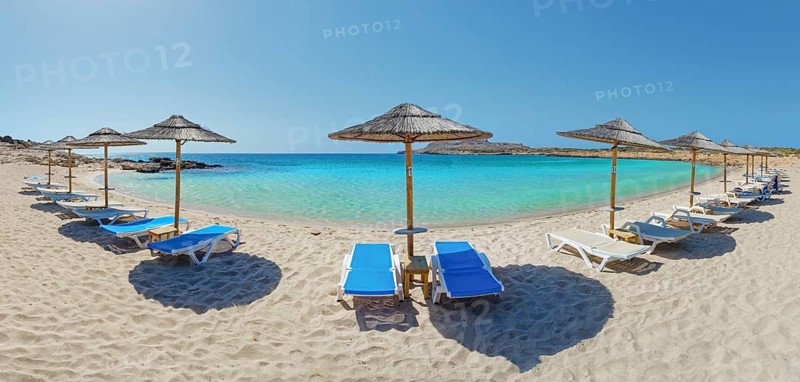 Sunny beach day at Diakoftis sandy beach with sun loungers under parasols in front of turquoise-coloured water, Diakoftis beach, Karpathos, Greece