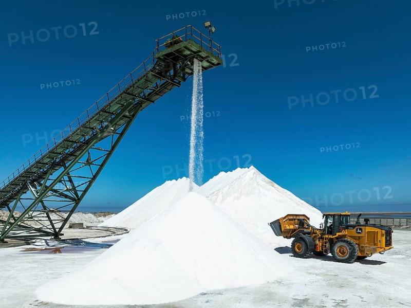 Salt heaps with conveyor belt and excavator at the Walvis Bay Salt works. Aerial view. Drone shot. Walvis Bay, Namibia