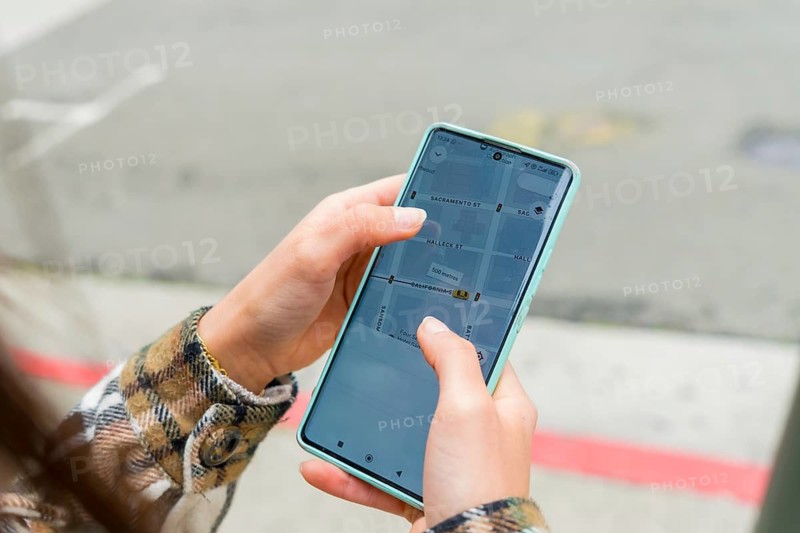 Person holding smartphone showing gps navigation app with san francisco street map, finding route and directions for walking or driving in an urban travel and commute setting