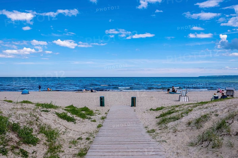 Wooden jetty leads to the quiet beach with blue sea and scattered people, Juliusruh, Breege, Rügen, Germany