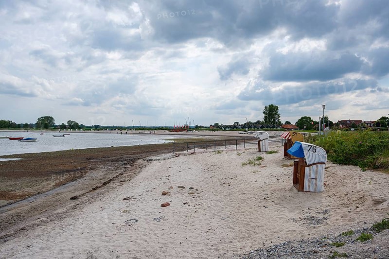 A quiet stretch of beach with beach chairs and boats under a cloudy sky, Hohwacht, Schleswig-Holstein, Germany