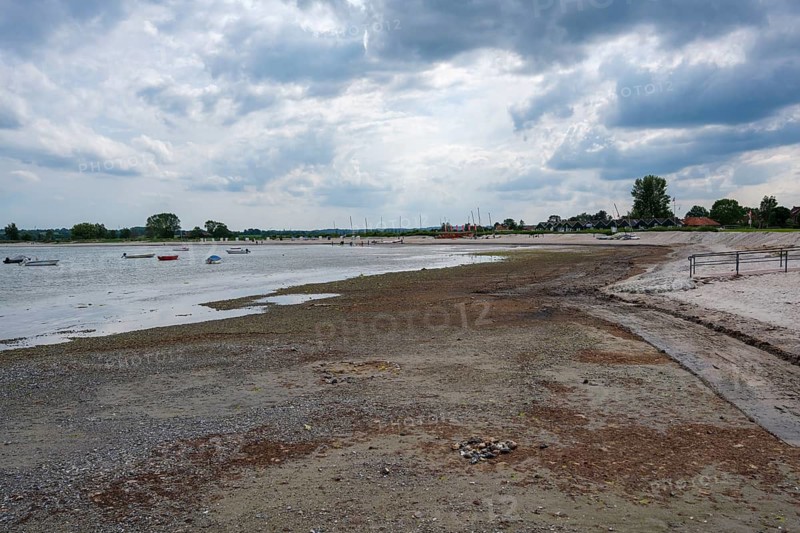 A wide beach under a cloudy sky, boats are visible in the distance, Hohwacht, Schleswig-Holstein, Germany