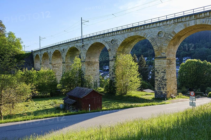 Large stone viaduct with several arches over a green landscape, bright sky and a small road, Rümlingen, Basel-Landschaft, Switzerland