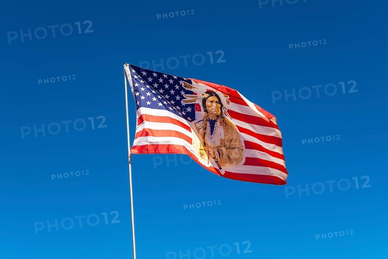 American flag with an indigenous chief's portrait flying proudly under a clear blue sky, symbolizing patriotism, heritage, and the cultural connection between the usa and its native peoples