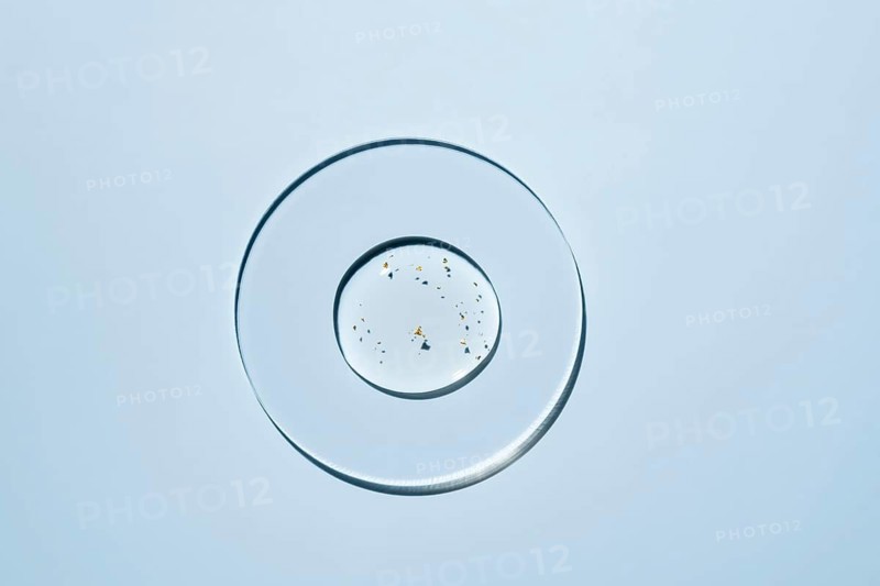 A minimalist design glass plate features delicate specks of gold The composition rests on a light blue background, creating a sense of elegance and simplicity