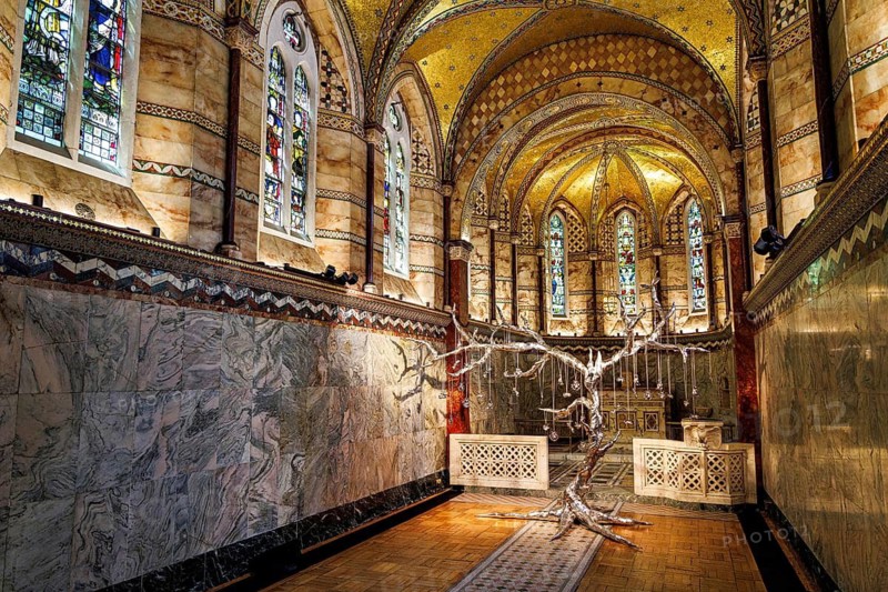 Silver tree sculpture stands beneath stained glass in the marble chancel of Fitzrovia Chapel, London, England, United Kingdom