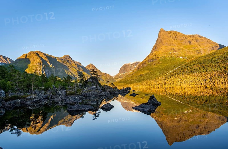 Picturesque mountain landscape with Innerdalstårnet peak in the Innerdalen high valley, mountain peaks reflected in Lake Innerdalsvatna, in the evening light at sunset, Trollheimen Mountain Area, Sunndal, Møre og Romsdal, Norway