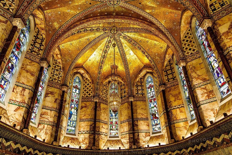 Gilded mosaic vaulting and stained glass windows illuminate the apse of the Grade II listed Fitzrovia Chapel, London, England, United Kingdom