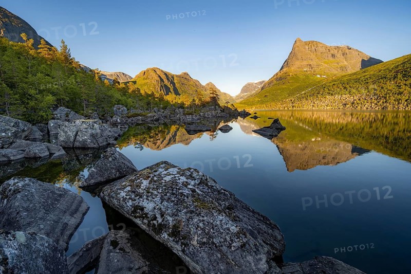 Picturesque mountain landscape in the Innerdalen high valley, Innerdalstårnet peak reflected in Lake Innerdalsvatna, in the evening light at sunset, Trollheimen Mountain Area, Sunndal, Møre og Romsdal, Norway