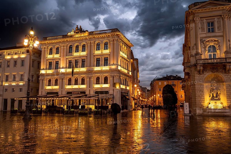Illuminated square Piazza Unità d'Italia, building on Via Orologio, with reflection, dramatic clouds, blue hour, old town, Trieste, Friuli-Venezia Giulia region, Italy