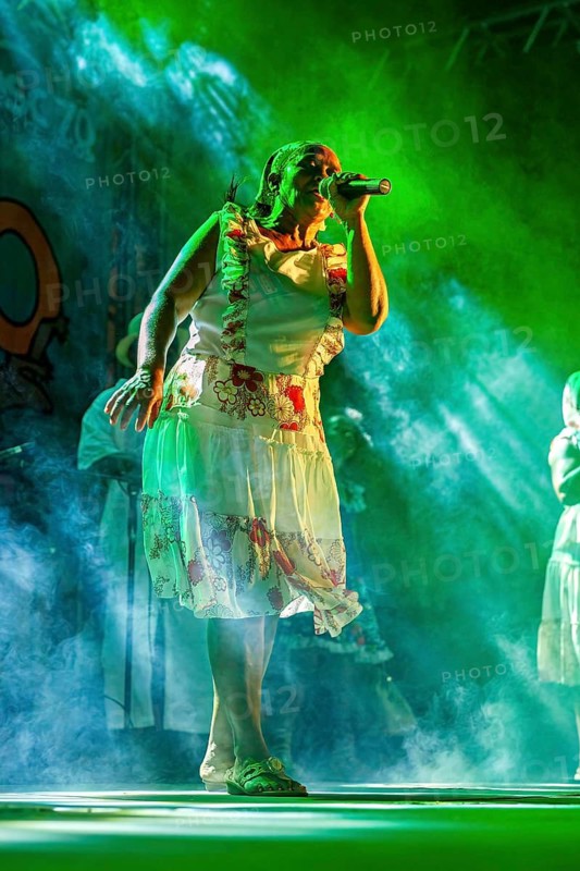 Singer wearing traditional clothes on a stage under green lights, a band playing and dancing at a festival in Petrolina in Brazil